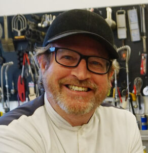 image of david britton smiling and wearing a black cap